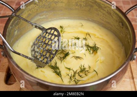 Donna che prepara purè di patate con lo schiacciapatate inossidabile. Processo di cottura, di purè di patate Foto Stock