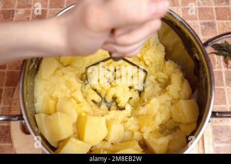 Donna che prepara purè di patate con lo schiacciapatate inossidabile. Processo di cottura, di purè di patate Foto Stock