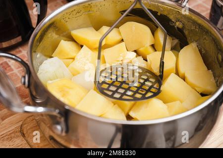 Donna che prepara purè di patate con lo schiacciapatate inossidabile. Processo di cottura, di purè di patate Foto Stock