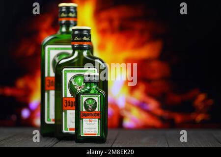 KIEV, UCRAINA - 4 MAGGIO 2022 Jagermeister bottiglia di alcol originale su tavolo di legno con camino rosso sullo sfondo. Produzione di alcool Elite Foto Stock