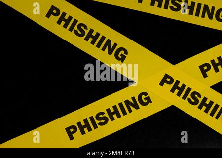 Avviso di phishing, attenzione e avviso. Nastro barricata giallo con phishing parola su sfondo nero scuro. Foto Stock