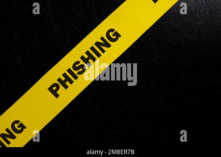 Avviso di phishing, attenzione e avviso. Nastro barricata giallo con phishing parola su sfondo nero scuro. Foto Stock