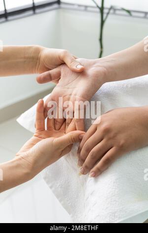 massaggio alle mani di un giovane, dettagli delle dita e delle articolazioni mentre si ha un controllo medico, benessere Foto Stock