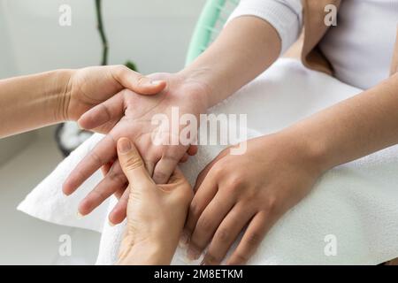 fare la terapia di massaggio alle mani di una giovane persona, i dettagli delle dita e delle articolazioni, benessere spa quando fare manicure, stile di vita Foto Stock