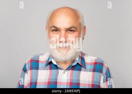Anziano caucasico viso vecchio. Vecchio uomo anziano maturo con barba grigia su sfondo grigio studio. Ritratto di un vecchio anziano calvo maturo con grigio Foto Stock