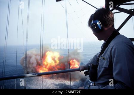 Un membro dell'equipaggio a bordo della nave da guerra USS WISCONSIN (BB-64) guarda come una delle pistole Mark 7 16-inch 50-calibro della nave è sparato. Questo è l'ultimo sparo di armi DEL WISCONSIN prima della sua disattivazione. Paese: Oceano Atlantico (AOC) Foto Stock