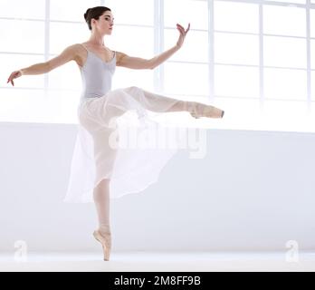 Controllo e perfezione. Ballerina giovane aggraziata in bianco danzante en pointe. Foto Stock