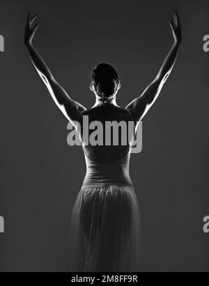 Grazia in ogni curva. Silhouette di una giovane ballerina che danza su sfondo scuro. Foto Stock