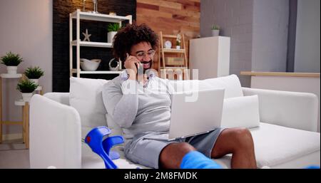 Felice Giovane con gamba rotta seduti sul divano a parlare sul telefono cellulare Foto Stock