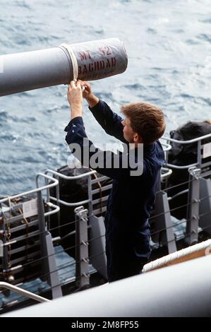 GUNNER's Mate 2nd Class Danny Medlock collega una copertura sopra la museruola di una delle pistole Mark da 28 5 pollici/38 pollici del Monte 52 a bordo della nave da guerra USS WISCONSIN (BB-64) durante l'operazione Desert Storm. Soggetto operativo/Serie: SCUDO DEL DESERTO Paese: Golfo Persico Foto Stock