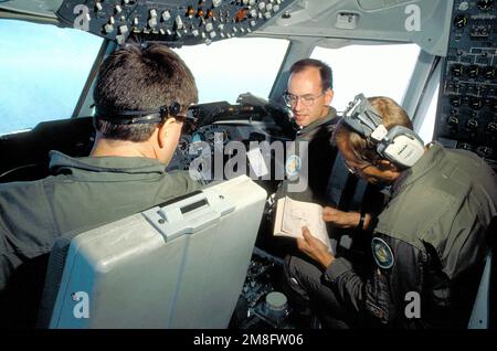 I membri di un equipaggio aereo di 6th Aerial Refuelling Squadron monitorano i controlli nell'abitacolo del loro aereo Strategic Air Command KC-10A Extender durante un volo tra March Air Force base, Calif. E Lincoln, Neb. L'equipaggio comprende, da sinistra: CPT Mike Hoolihan, pilota, TSGT Jack Henry, ingegnere di volo e CPT Randy Witham, co-pilota. Paese: Sconosciuto Foto Stock