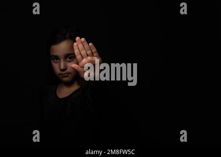 Bambina che mostra la mano di segnalazione per smettere utile per la campagna contro la violenza e il dolore. Smettete di abusare della violenza. Violenza, terrore, Un bambino spaventoso Foto Stock