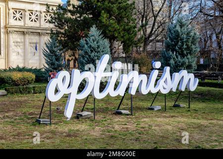 Bucarest, Romania, 2 gennaio 2022: Parola ottimista visualizzata di fronte al rumeno Atheneum Ateneul romano), edificio circolare che è la conce principale Foto Stock