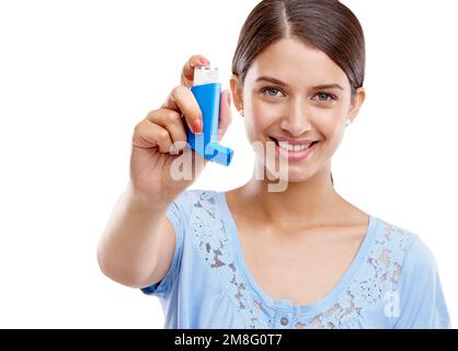 Donna, pompa di asma e sorriso per respirazione, sollievo o respirazione su uno sfondo bianco studio. Ritratto di una femmina isolata che tiene l'inalatore per Foto Stock