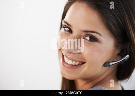 Qui per aiutarti 24 ore su 24. Ritratto di una giovane donna d'affari seduta su sfondo grigio. Foto Stock