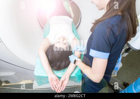 Il tecnico di scansione TC si affaccia sul paziente nello scanner di tomografia computerizzata durante la preparazione della procedura. Paziente donna che entra nello scanner TC. Foto Stock
