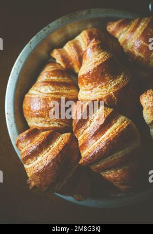 Una vista verticale dall'alto di croissant francesi appena fatti in una ciotola su sfondo nero Foto Stock