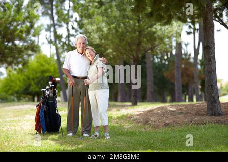 Golfisti felici. Ritratto completo di una coppia anziana felice in piedi con una borsa di mazze da golf su un campo da golf. Foto Stock