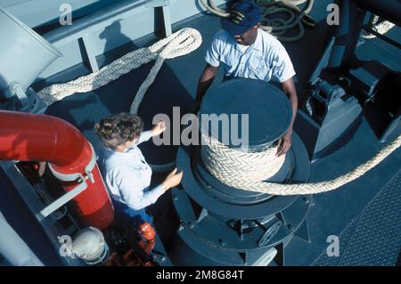 I compagni della marina, uomini e donne, a bordo del grande RIMORCHIATORE PORTUALE WENATCHEE (YTB-808) condividono le faccende di gestione della linea mentre la YTB si affianca a un rimorchio. Base: Naval Air Station, North Island Stato: California (CA) Paese: Stati Uniti d'America (USA) Foto Stock