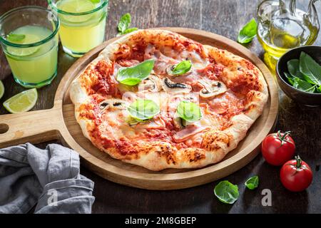 Pizza tradizionale Capricciosa su tavolo di legno. Cucina italiana classica. Pizza Capricciosa con prosciutto, formaggio e funghi. Foto Stock