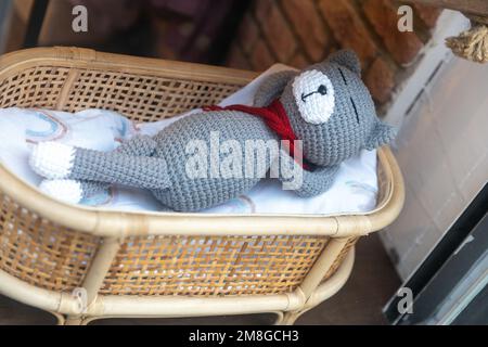 Gattino a maglia grigio divertente dorme in un cesto di vimini Foto Stock