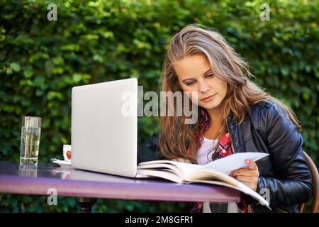 Usufruendo al massimo della connessione wi-fi gratuita per il bistrot. Ritratto di una bella adolescente che lavora sul suo computer portatile in un bistrot. Foto Stock