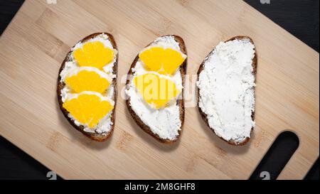 Tostatura con formaggio di ricotta e arancia su un tagliere Foto Stock