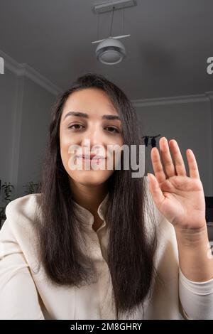 Ritratto di testa di felice donna millenaria che agita la mano. Ciao o ciao alla fotocamera dello smartphone. Idea di videochiamata. Sorridente dipendente freelance. Foto Stock
