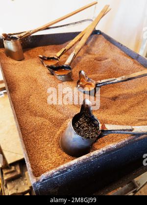 Preparazione di caffè naturale in turchi sulla sabbia. Caffè turco Foto Stock