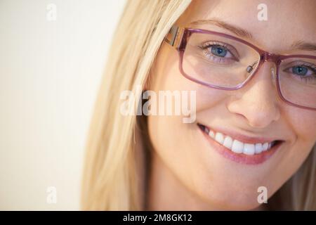 Carino e intelligente. Primo piano di una bella giovane donna che indossa occhiali e sorridente. Foto Stock