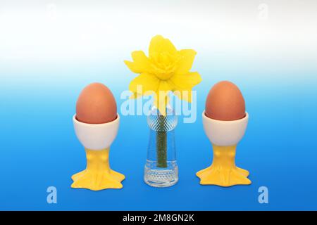 Colazione per due con uova sode in coppe novelle, fiore di daffodil in vaso retrò. Primavera, Pasqua, bella natura, concetto di cibo sano. Foto Stock