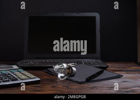 Lampada a incandescenza ordinaria e ufficio. Lampadina e calcolatrice. Lampada di vetro sul tavolo. Foto Stock