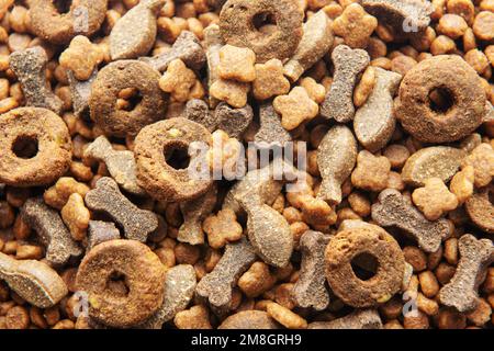 Cibo secco per cani di forme diverse come sfondo alimentare. Cibo sano per cani Foto Stock