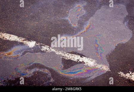 Fuoriuscita di benzina sull'asfalto con una striscia divisoria bianca in un parcheggio come una texture o sfondo. Foto Stock