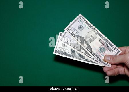 100 e 50 dollari di fatture tiene in mano su sfondo verde 100 e 50 dollari fatture. Carta da parati business e finanza Foto Stock