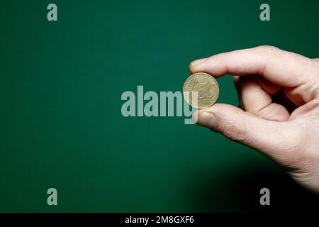 moneta da 50 cent pizzicata con le dita su fondo verde Foto Stock