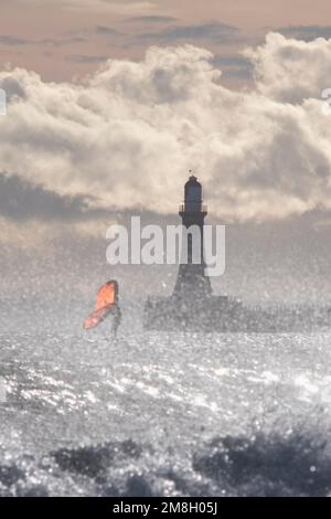 Sunderland, Regno Unito, 14 gennaio 2023. Un windsurf cavalca le onde dal molo dei Roker a Sunderland. Il tempo è previsto per ottenere molto più freddo come bassa pressione davanti si muove in Domenica. (c) Paul Swinney/Alamy Live News Foto Stock