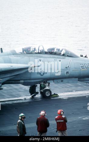 Gli equipaggi della piattaforma di volo osservano come un equipaggio holdback/hookup controllare i collegamenti degli ingranaggi del naso di un aereo di Fighter Squadron 32 (VF-32) F-14A Tomcat sulla portaerei USS JOHN F. KENNEDY (CV-67). Paese: Mare Adriatico Foto Stock