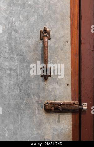 Vecchia maniglia della portiera arrugginita e chiusura a scatto sullo sportello in lamiera usurata, primo piano Foto Stock