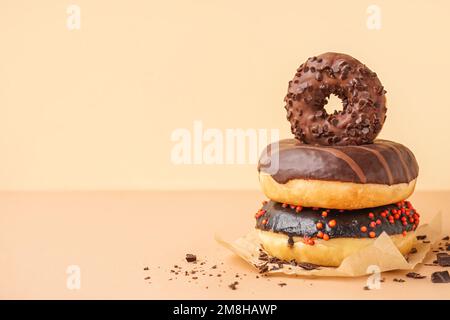 Pergamena con deliziose ciambelle al cioccolato su sfondo beige Foto Stock