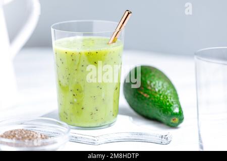 Frullato verde in vetro servito con paglia. Prodotto con semi di kiwi e chia. Super cibo e antiossidante per uno stile di vita sano Foto Stock