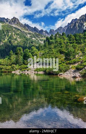 Bellissimo paesaggio estivo di alti Tatra, Slovacchia - lago di Poprad, foresta lussureggiante, rocce in acqua pura, montagne e nuvole bianche sul cielo Foto Stock