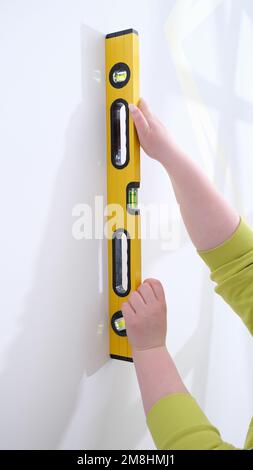 Le mani di lavoro controllano l'uniformità della parete con l'attrezzo speciale per la misurazione del livello Foto Stock