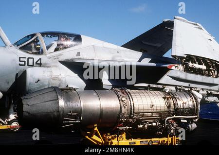 Un motore a turbojet Pratt & Whitney J-52-P-8B poggia su un carrello di trasporto del motore sul ponte di volo della portaerei a energia nucleare USS ABRAHAM LINCOLN (CVN-72). L'aereo nella parte posteriore della foto è un A-6E Intruder of Attack Squadron 95 (VA-95). L'A-6E è alimentato da due di questi motori. Paese: Pacifico occidentale Foto Stock