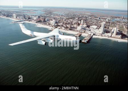 Una vista laterale aria-aria di un 438th Airlift Wing, C-141 Starlifter, che sorvola l'Oceano Atlantico con Atlantic City sullo sfondo. Il C-141, coda #70166, con una fusoliera dipinta di bianco è usato per trasportare alti funzionari civili e militari. Data esatta dell'acquisizione sconosciuta. Base: McGuire Air Force base Stato: New Jersey (NJ) Paese: Stati Uniti d'America (USA) Foto Stock