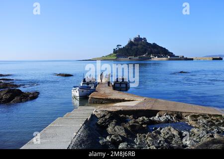 Uomini di traghetto in attesa sulla terraferma per il trasporto dei turisti a St. Monte di Michele in alta marea, Cornovaglia, Regno Unito - John Gollop Foto Stock