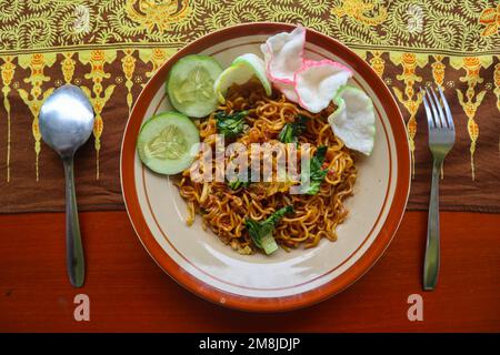 mie tek tek o spaghetti fritti fatti con tagliatelle di uovo con pollo, cavolo, verde di senape, polpette, uova strapazzate. cibo indonesiano Foto Stock