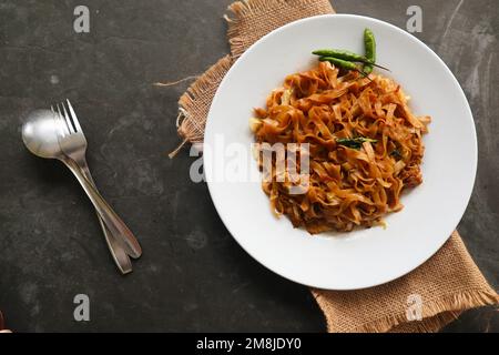 Kwetiau goreng è cinese indonesiano mescolato piatto piatto di pasta di riso fatto da kwetiau, mescolato fritto in olio da cucina con aglio, cipolla, manzo, pollo, Foto Stock