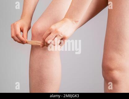 Applicazione delle mani, adesivo adesivo adesivo, cerotto, cerotto sulla pelle ferita del ginocchio per la protezione. Foto di alta qualità Foto Stock