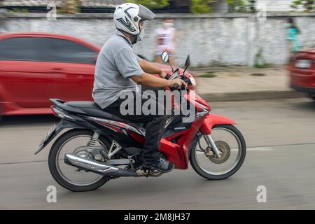 SAMUT PRAKAN, THAILANDIA, 21 2022 MAGGIO, Un uomo con casco cavalca una moto per strada Foto Stock